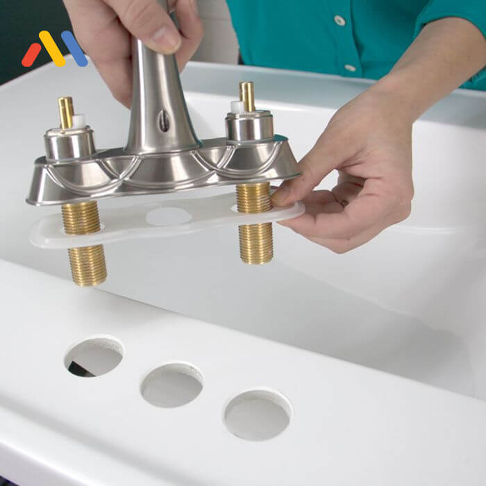 Đặt vòi nước vào các lỗ lắp trên bồn rửa mặt